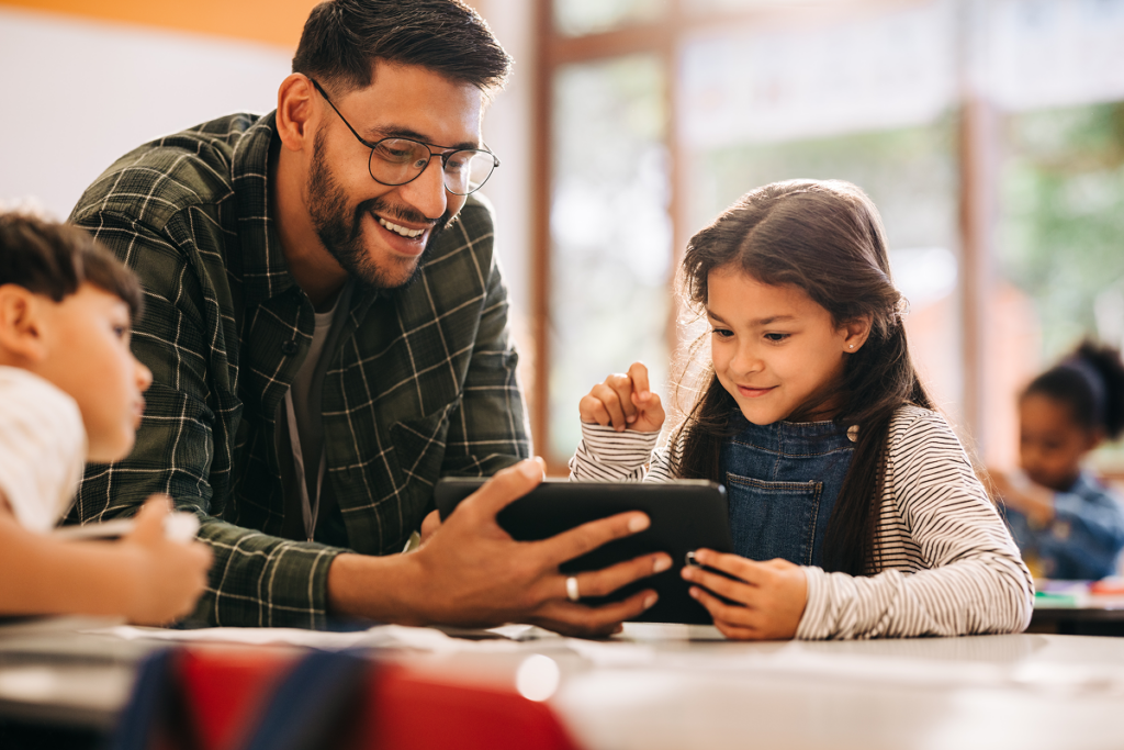 Professor mostra tablet para aluna criança.