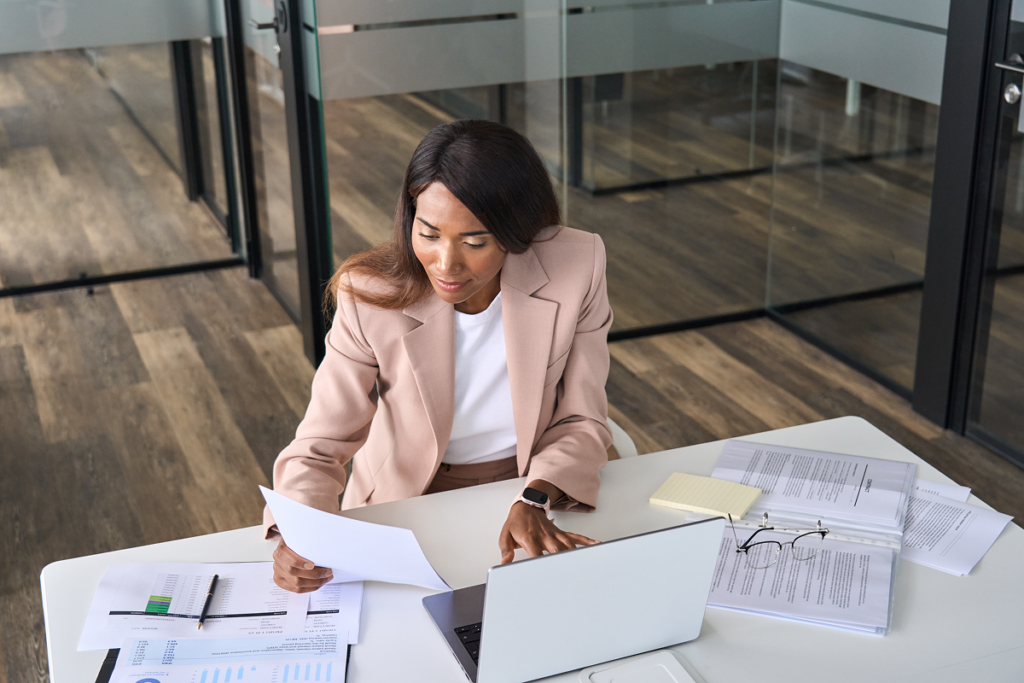 Mulher em escritório analisando um currículo em frente ao computador. o que colocar em habilidades no currículo.