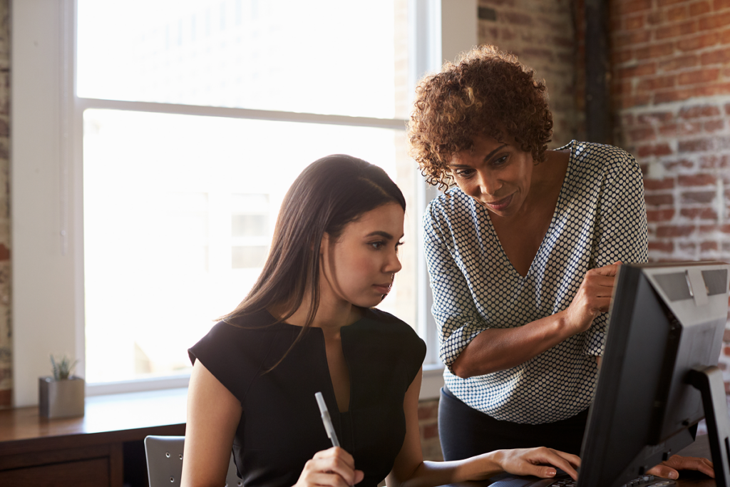 Mulher observa sua colega de trabalho e a orienta. Feedback negativo.